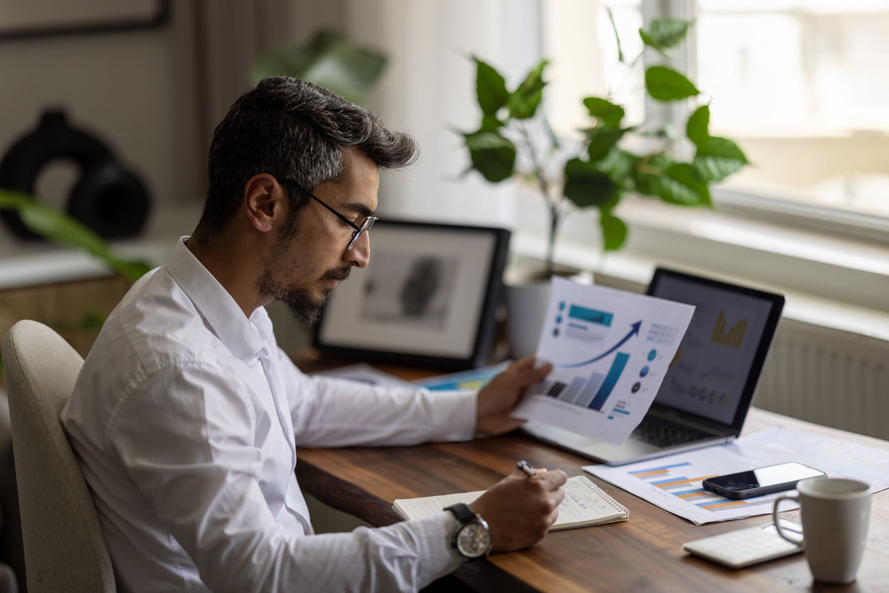 An Accountant Takes Notes on a Pad While Reviewing Financial Graphs..jpg