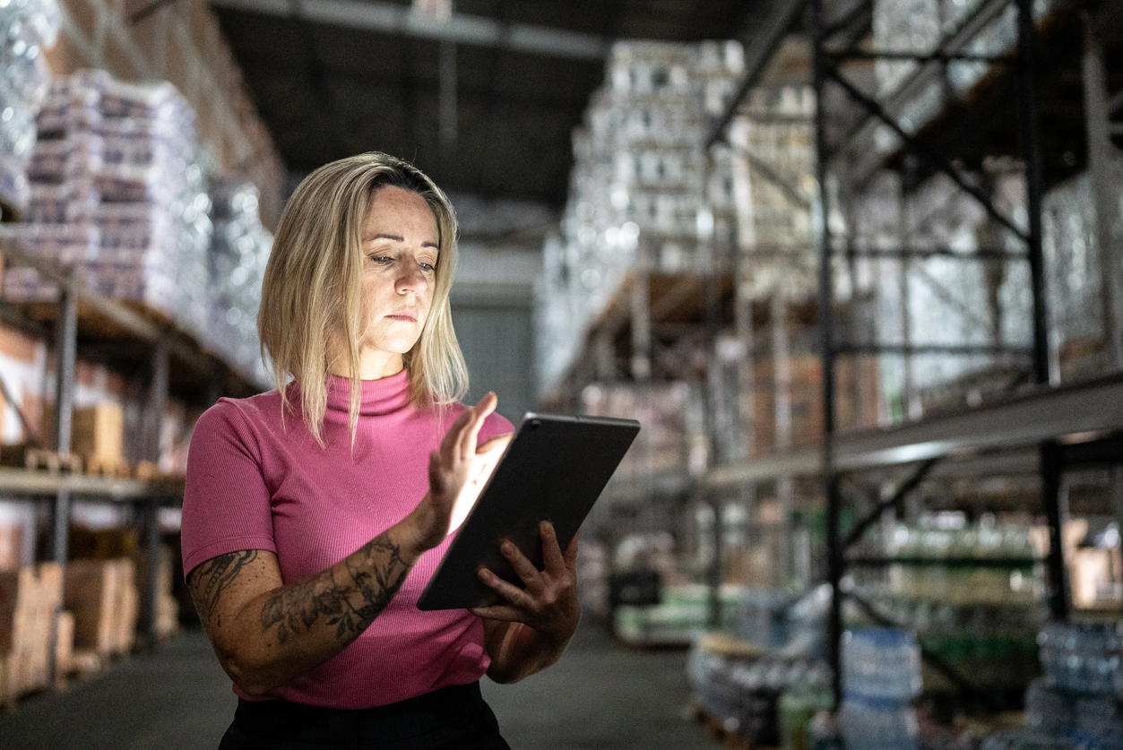 Supply chain analyst working on a tablet in a warehouse.